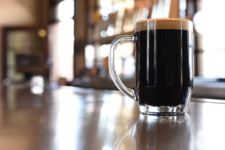 A full glass of stout sits on a bartop.